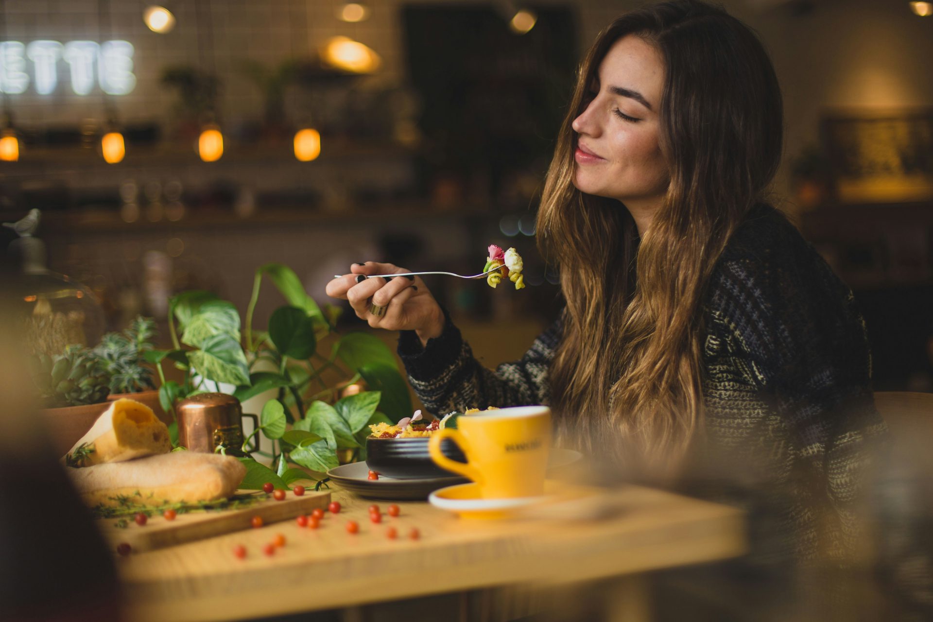 Une femme tenant une fourchette devant une table.